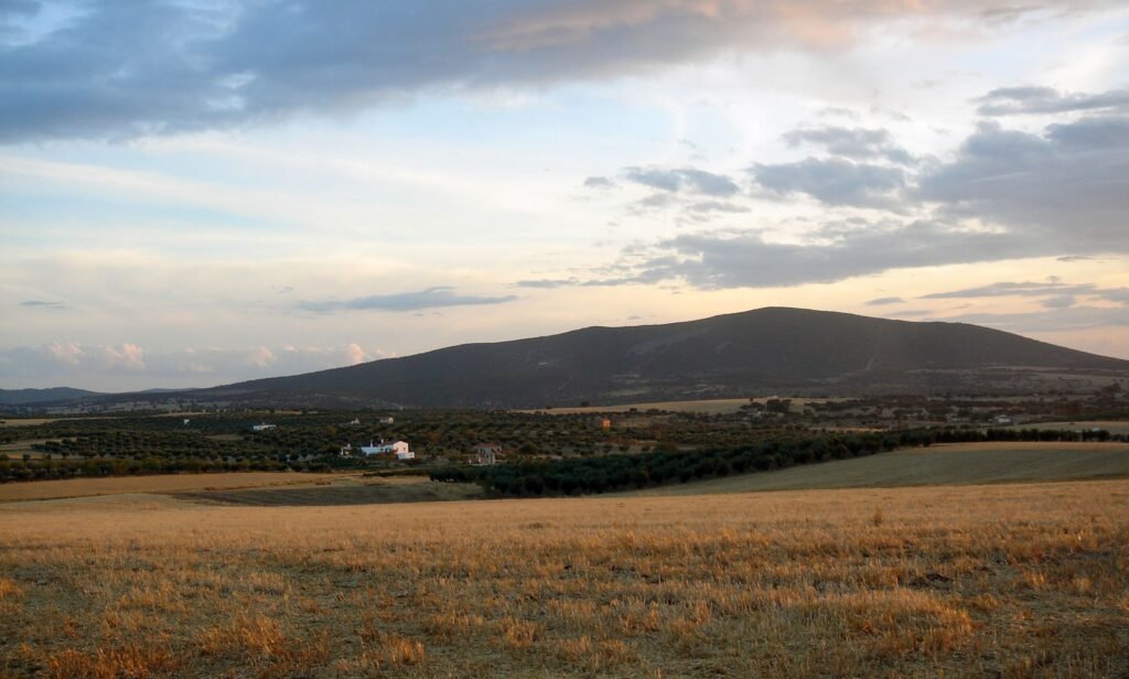 Peaceful rural landscape with fields and mountains in La Haba, Spain at sunset.